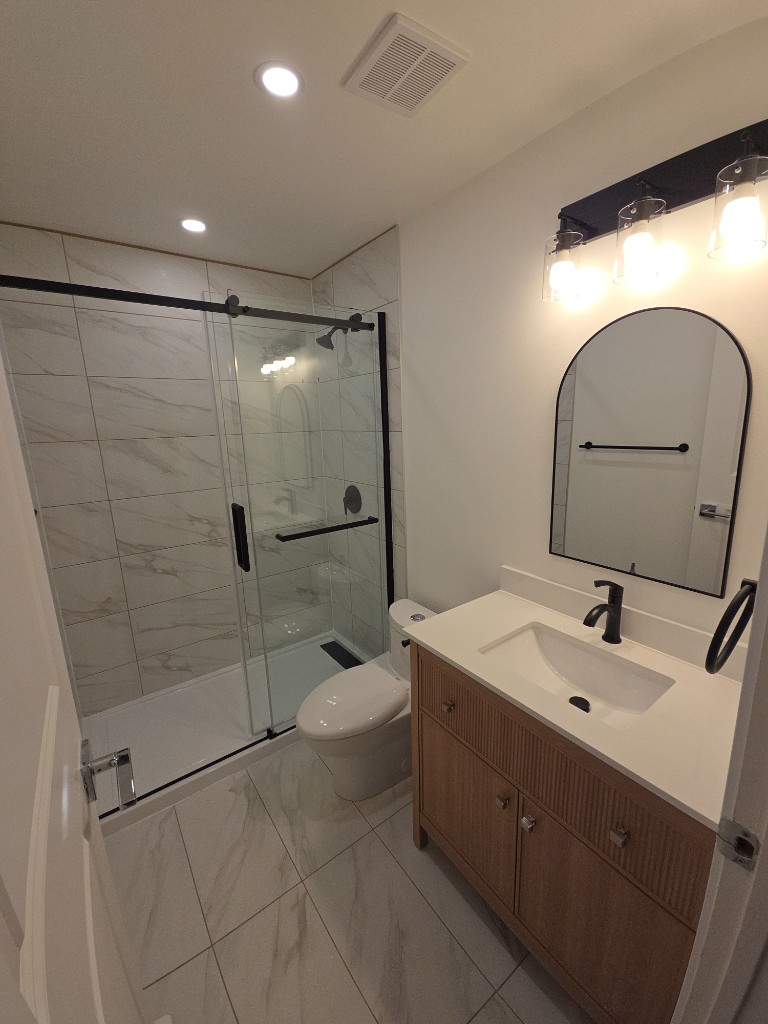 Residential renovation: modern bathroom with wood vanity and walk-in shower by BNA HOME